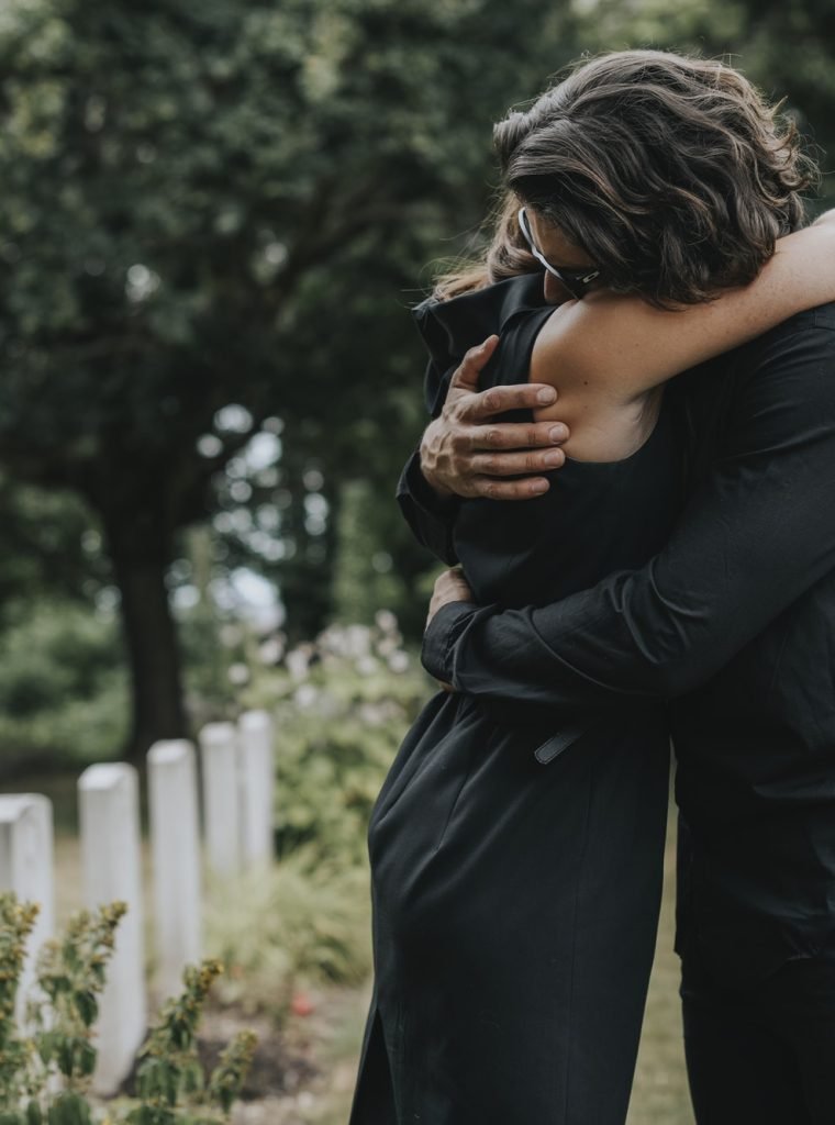 husband-trying-to-comfort-his-wife-at-a-graveyard.jpg husband-trying-to-comfort-his-wife-at-a-graveyard.jpg